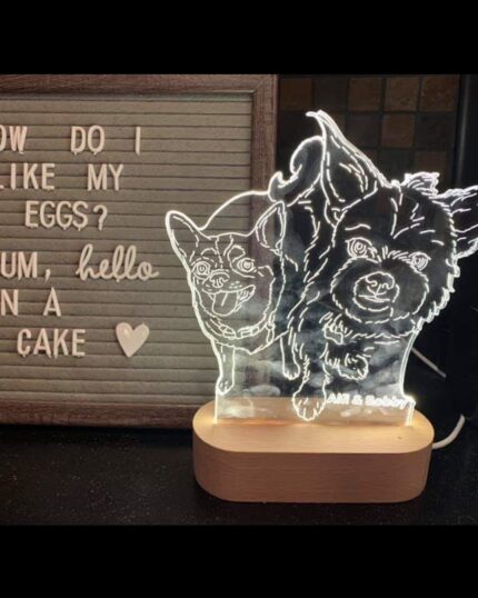 A light-up Customized Pet Lamp Design featuring two small dogs sits beside a letter board that says, “How do I like my eggs? Um, hello, in a cake.” A heart below offers perfect inspiration for your next custom pet keepsake.