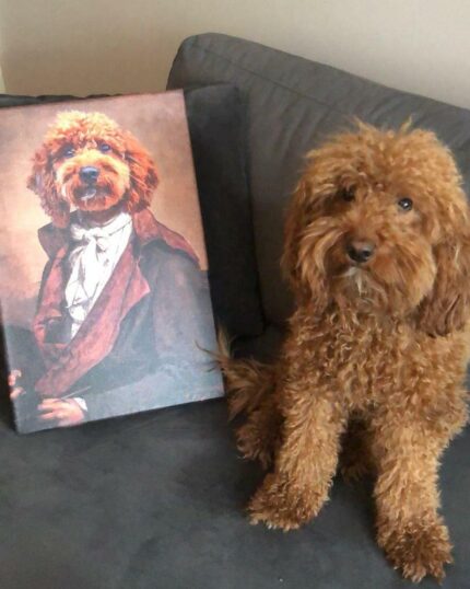A curly-haired brown dog sits on a gray couch beside The Noble Gentleman #1 - Custom Pet Canvas, which features a portrait of a similar dog dressed in historical, formal attire.