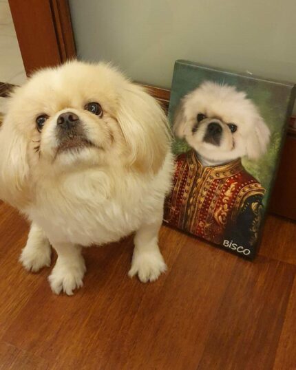 A fluffy cream-colored dog sits on a wooden floor next to a custom design pet canvas—a portrait of itself dressed in ornate, royal-style clothing with the name Bisco on the painting.