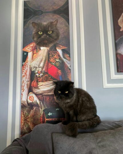 A fluffy black cat lounges on a gray couch in front of "The King #3 - Custom Design Canvas Painting," humorously highlighting the pet's uncanny resemblance to the elaborate historical portrait.