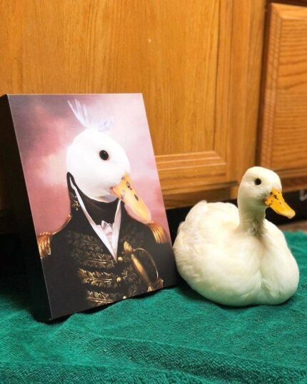 A white duck sits on a green towel beside the Special Design Canvas Painting – Noble Gentleman #10, which features a duck in a historic military uniform, both placed in front of wooden cabinets.