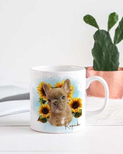 The Flower Wreath Custom Design Mug #1 is a white mug featuring an illustrated French Bulldog puppy with sunflowers, styled next to an open magazine and a potted cactus—ideal for fans of pet-themed custom design art.