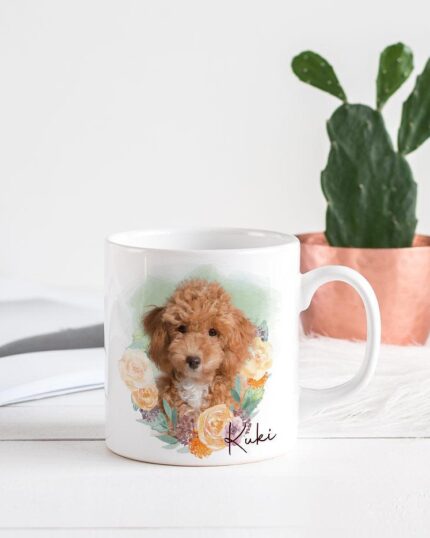 The Flower Wreath Custom Design Mug #1, featuring a curly-haired puppy and flowers with "Ruki" printed on it, sits beside an open book and a potted cactus, highlighting its charming custom pet canvas style.