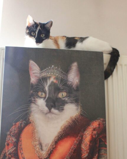 A calico cat lounges on a radiator, gazing over The Noble Lady #8 - Custom Design Pet Canvas, which shows her royally adorned in a jeweled crown and an ornate red and gold Renaissance gown.