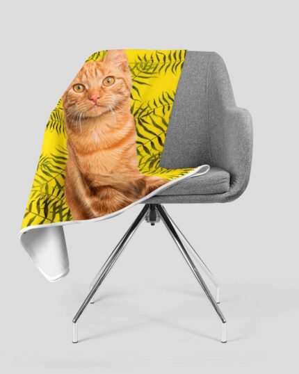 A gray chair with metal legs holds a Custom Design Pop-Art Blanket – Leaf #12, which features a photo of an orange tabby cat and green leaves on a bright yellow background inspired by pet canvas designs.