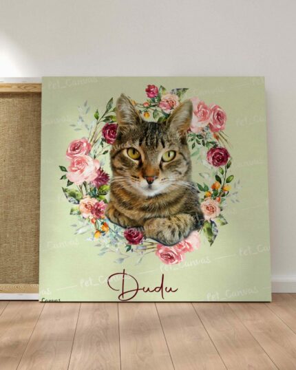 A custom design pet canvas featuring a tabby cat surrounded by a wreath of colorful flowers, with the name Dudu in cursive at the bottom, leaning against a wall on a wooden floor.