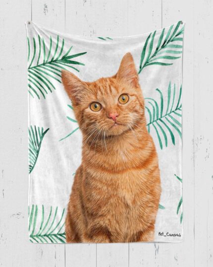 A Personalized Pop-Art Blanket – Leaf Collection is draped over a sofa, showcasing an orange tabby cat illustrated with green palm leaves on a white background.