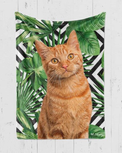 A ginger tabby cat sits before green tropical leaves and a black-and-white zigzag pattern, showcasing the Custom Design Pop-Art Blanket – Leaf #4, perfect for adding personality to any space.