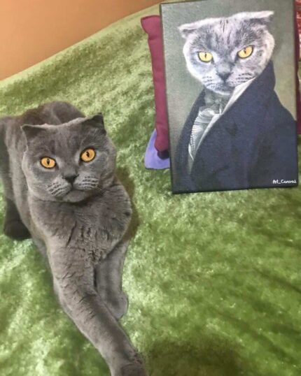 A gray cat with yellow eyes lounges on a green blanket beside The Noble Gentleman #8 - Custom Design Pet Canvas, which features its portrait in a suit matching the same pose and expression.