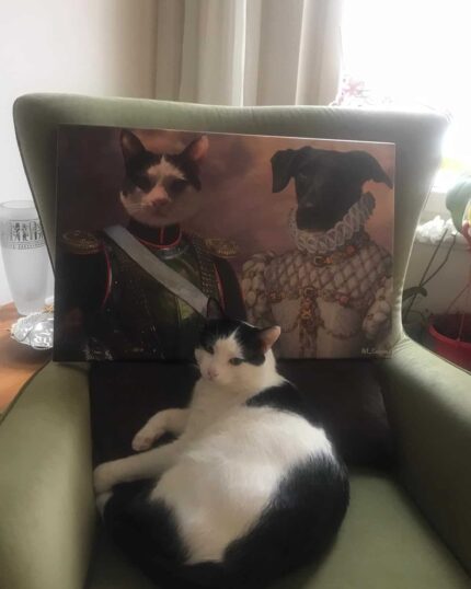 A black and white cat lounges on a green armchair beneath a "Multiple Portraits #7 General and Noble Lady" custom canvas, humorously depicting a regal cat and dog in historical costumes as sunlight streams in through the window.