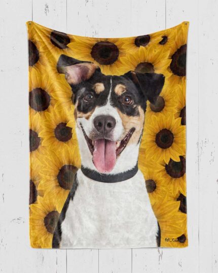 A cheerful black, white, and tan dog with its tongue out is pictured on the Custom Design Pop-Art Blanket – Sunflower, featuring a bright yellow sunflower pattern and displayed on a white wooden wall.