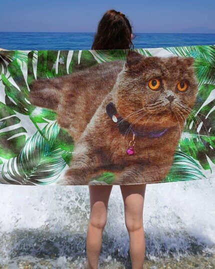 A person stands on a pebbly beach facing the sea, holding the Custom Design 3D Printed Beach Towel – Blueberry, as waves gently crash at their feet.
