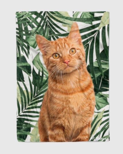 A realistic orange tabby cat sits before lush green tropical leaves, gazing curiously—featured on our Custom Design Pop-Art Blanket – Leaf #5, ideal for unique and personalized pet-themed décor.