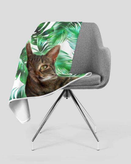 Showcase your pet on the Custom Design Pop-Art Blanket – Leaf #3, featuring a gray chair with a blanket, a tabby cat, and green tropical leaves on white—ideal for stylish, personalized decor.
