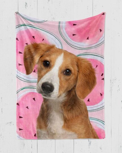 A light brown and white dog with floppy ears sits in front of the Custom Design Pop-Art Blanket – Watermelon, which features a pink watermelon pattern, with a custom pet canvas displayed against a white wooden wall.