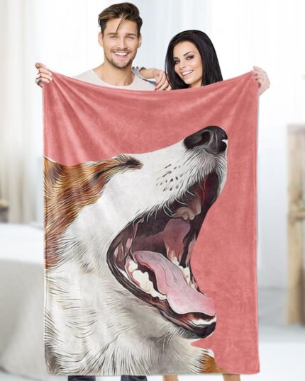 A smiling man and woman stand indoors, holding up a pink Custom Design Pop-Art Blanket – Solid Colors featuring a large, realistic image of their dog. The room has soft lighting and neutral decor.