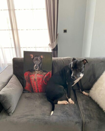 A black and white dog sits on a gray couch beside The Noble Red Lady #9 - Custom Design Pet Canvas, which shows a regal dog in red. The couch is set against a light wall with sheer curtains and sunlight streaming through behind.