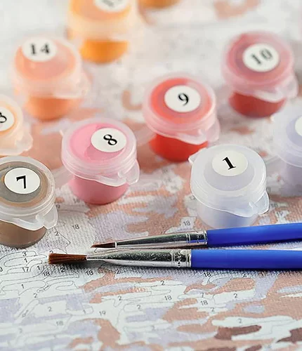 Close-up of small numbered paint pots, two blue-handled brushes, and a custom pet canvas with numbered areas—Handmade Paint by Number Kit for creating your own unique painted pet portrait.