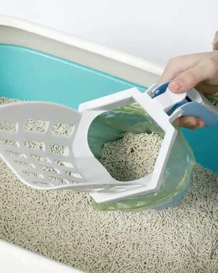 A hand holds the LitterLux Advanced Cat Litter Scoop with a built-in green bag slot above a blue and white litter box with light-colored pellets—ideal for cleanup before showcasing your custom pet canvas.