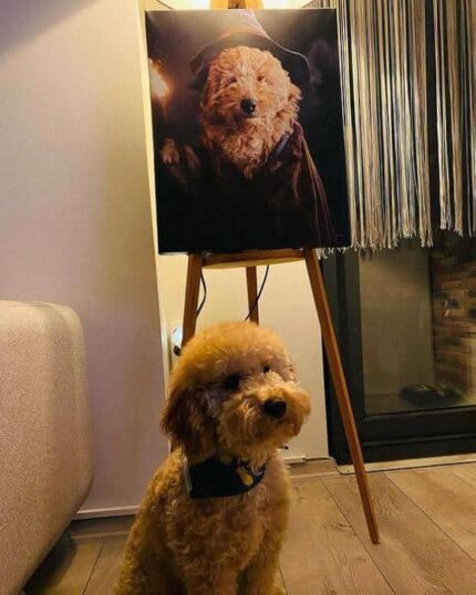 A fluffy brown dog sits on a wooden floor by "The Wizard Gandalf – Custom Design Pet Canvas" on an easel, featuring the dog in costume. The cozy room has a sofa, fireplace, and metallic streamers to the side.