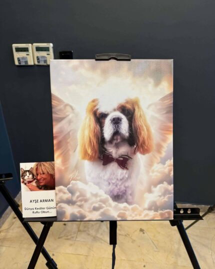 The Angelic Paws – Custom Design Pet Canvas, shown framed on an easel, features a dog with angel wings among clouds. A card beside it depicts a woman and cat with Turkish text, all set against a plain dark wall.