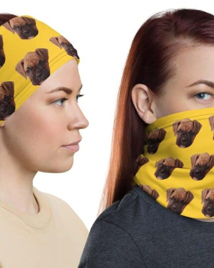 Two women with straight, reddish-brown hair wear yellow accessories featuring brown dog faces—one a Custom Neck Gaiter With Pet Faces over her nose and mouth, the other a headband. Both display neutral expressions and a pet canvas-inspired style.