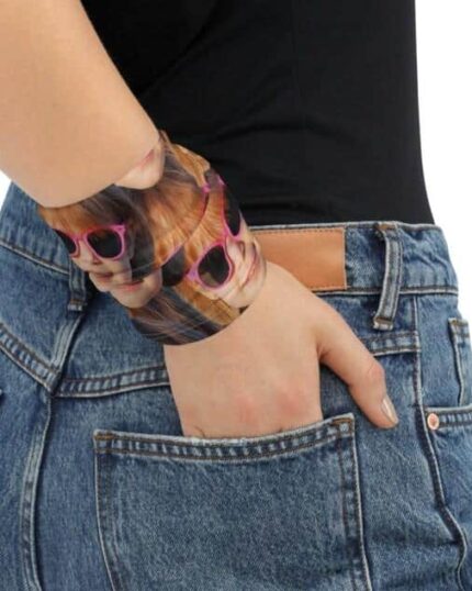 A person in blue jeans and a black top stands against a plain white background, wearing a Custom Neck Gaiter With Pet Faces that features printed images of a face in sunglasses. Their hand rests in their pocket.