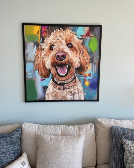 A Custom Design Abstract Pet Portrait of a smiling, curly-haired dog hangs in a frame on a light gray wall above a beige sofa decorated with textured cream, gray, and blue pillows.