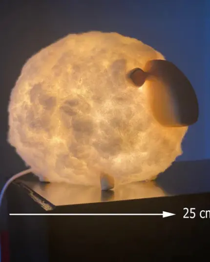 The Soft Cotton Sheep Night Light, measuring 25 cm in length, emits a warm glow as it sits on a dark surface—perfect for pairing with your custom design pet canvas or unique canvas printing décor.